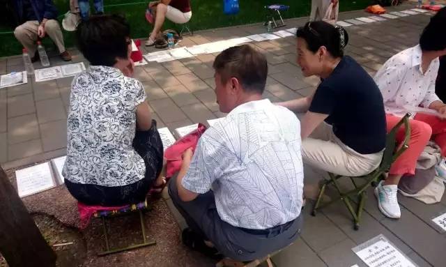 中山公园相亲角的三位大爷大妈坐在一起交流相亲经验.摄影/费知.